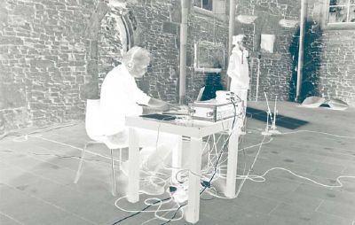 Negativbild Mann mit Kopfhörern sitzt an Tisch und bedient Audioequipment