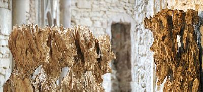 4 Holzfiguren blicken auf eine fünfte vor einer Kirchenwand